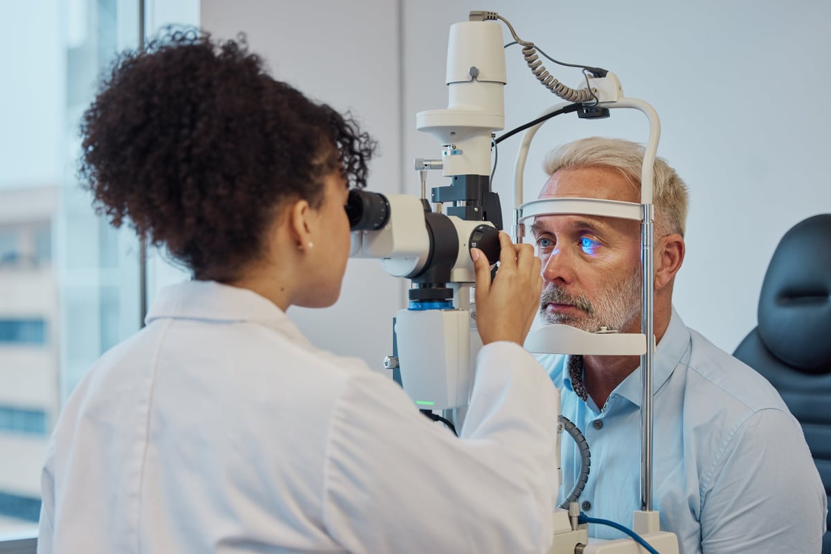 Visión, examen de ojos y atención médica con un médico mujer u optometrista examinando los ojos de un paciente masculino en una clínica